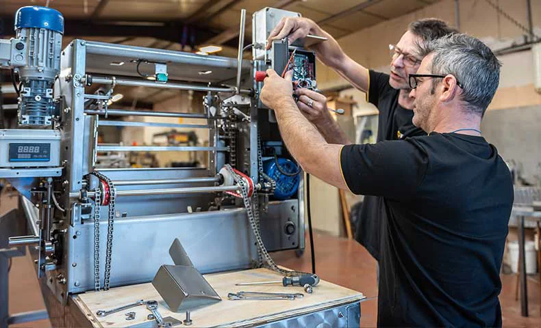 Techniciens ajustant une machine de production apicole en inox