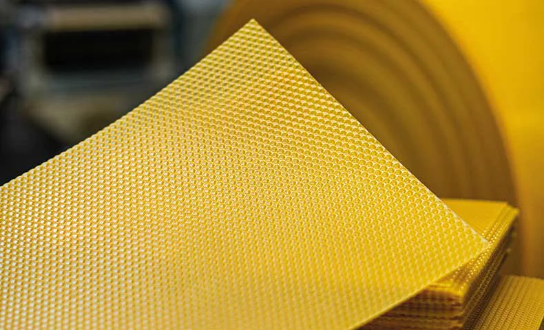 Plaque de cire gaufrée en cours de fabrication avec rouleaux en arrière-plan